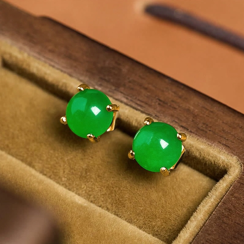 Bright emerald green jade stud earrings in gold setting on velvet jewelry tray close-up