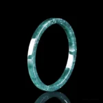 Natural jade thin bangle bracelet front view polished dark green with white speckles on black background
