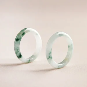 Polished natural jade rings shown in three-quarter side view showcasing distinct green mottling and smooth band texture