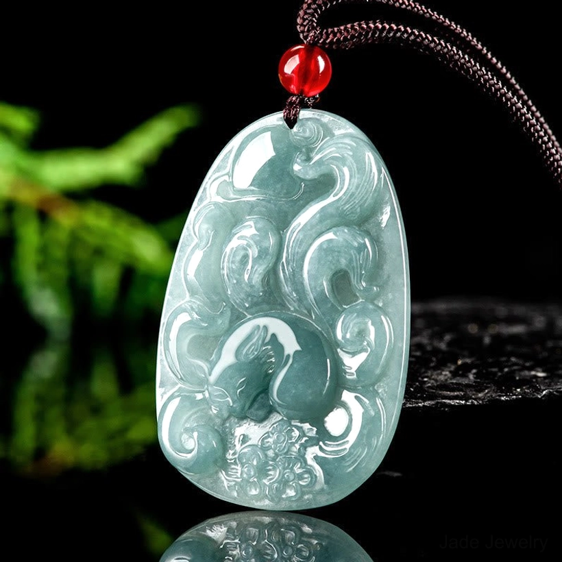 Nine-tailed fox jade pendant from three-quarter angle, displaying detailed relief carving with flowing scroll designs and smooth polished surface