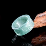 Natural jade om mani padme hum carved prosperity ring top view showing intricate engraved mantra text on pale blue-green jade