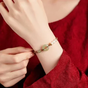 Woman adjusting jade peace buckle luck bracelet on wrist with red textured clothing