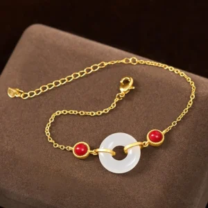 Adjustable peace buckle jade bracelet side view on velvet cushion, featuring lobster clasp and dual red beads with polished white jade ring