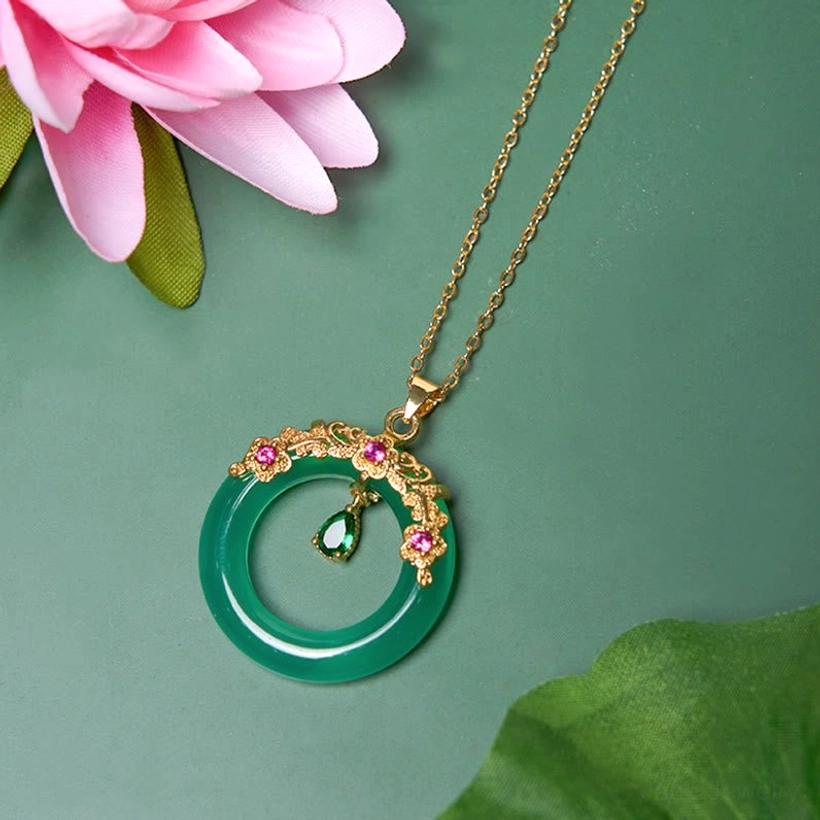 Peace buckle pendant close-up with pink lotus leaves and dark green background