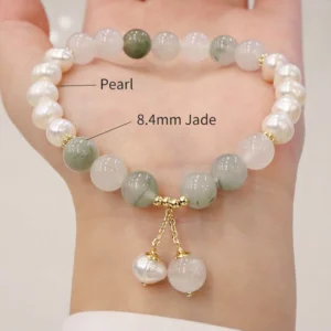 Pearl and jade beaded bracelet worn on wrist showing mixed freshwater pearl and jade stone beads with gold drop pendants
