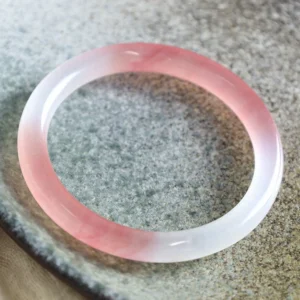 Top-down view of pink golden silk jade bangle showing smooth polished translucent surface with natural color gradient