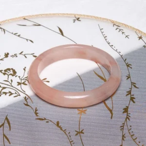 Pink Golden Silk Jade round bangle bracelet on traditional Chinese floral tray