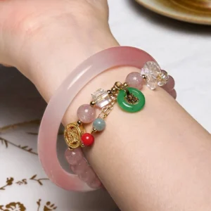 Worn pink golden silk jade bangle and strawberry quartz bracelet on wrist, showing love and protection bundle styling