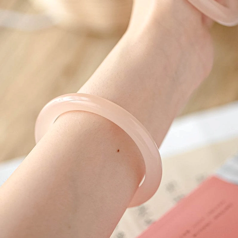 Pink jade bangle worn on forearm close-up side view, smooth translucent rose jade fitting neatly on wrist