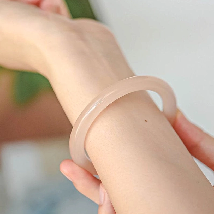 Pink jade bangle worn on wrist side view, translucent dusty rose stone fitting comfortably on human wrist
