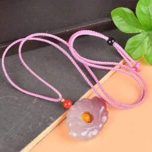 Braided pink rope jade lotus necklace lay flat on table with green leaf decor showing full necklace length