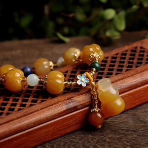 Close-up side view of Pixiu charm pendant on Golden Silk Jade wealth bracelet with dark green spacers