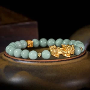 Three-quarter view of Pixiu jade prosperity bracelet with matte jade beads and carved gold Pixiu charm
