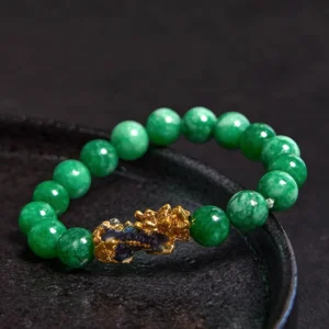 Gold Pixiu charm with cyan jade beads overhead view showing intricate enamel details