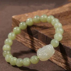 Natural Hetian jade Pixiu wealth bracelet three-quarter overhead view showing gradient green beads and hand-carved Pixiu charm