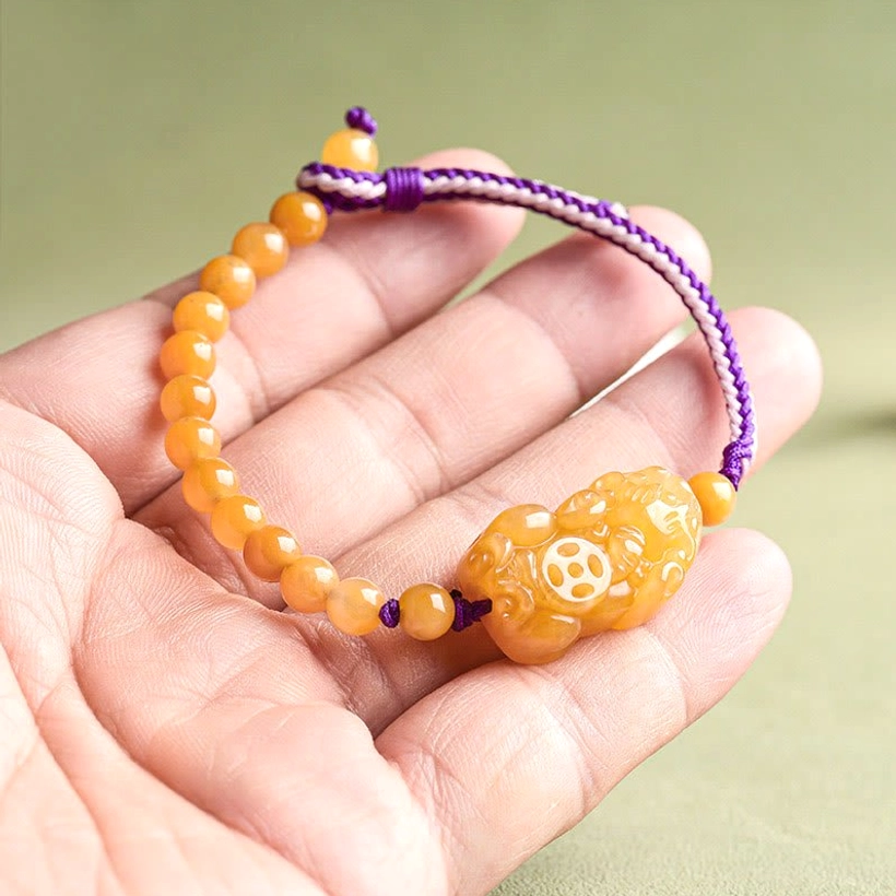 Pi Xiu jade bracelet detailed view showing smooth yellow beads purple woven strap and carved ornament