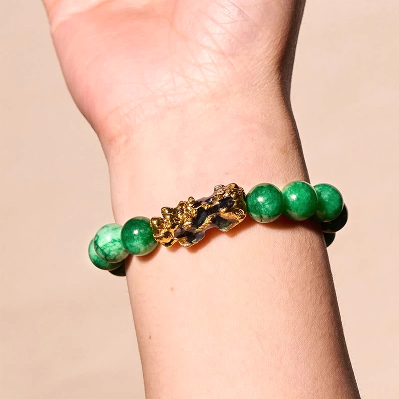 Cyan jade Pi Xiu wealth bracelet worn on wrist showing slim green jade beads and gold Pi Xiu charm, side view on-body wear demonstration