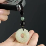 Pixiu jade peace buckle keychain with braided rope displayed alongside car remote key in close-up detail
