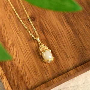 Pixiu jade wealth pendant necklace with polished white jade carving and fine gold-plated curb chain on wooden surface
