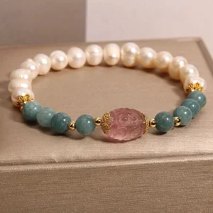 Top-down view of handmade gemstone bracelet showing pearl, jade, and strawberry quartz beads in circular layout