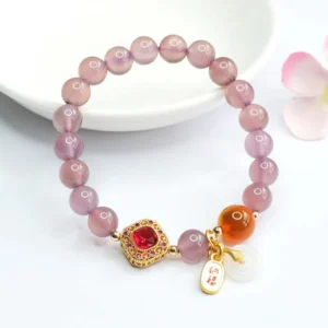 Purple chalcedony gemstone bracelet side view on white ceramic plate with floral styling