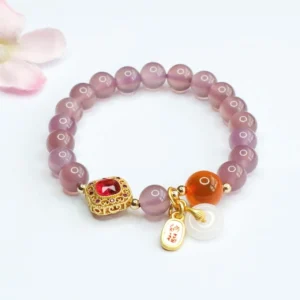 Purple chalcedony peace buckle bracelet with gold charm displayed on gray background with pink flowers