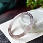 Purple golden silk jade bangle bracelet oblique side view showing polished variegated purple and brown tones
