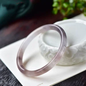 Purple golden silk jade bangle bracelet oblique side view showing polished variegated purple and brown tones