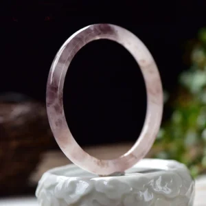 Round purple jade bangle bracelet front vertical view featuring natural stone veining on ceramic stand