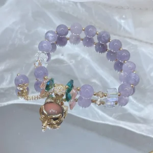 Close-up detail of purple jade fox bracelet showing mixed crystal decorations, fox pendant with brown inlay, adjustable chain design on satin fabric