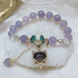 Purple jade fox charm happiness bracelet with light purple round beads, gold hardware, green crystal accents, and fox head pendant on white background