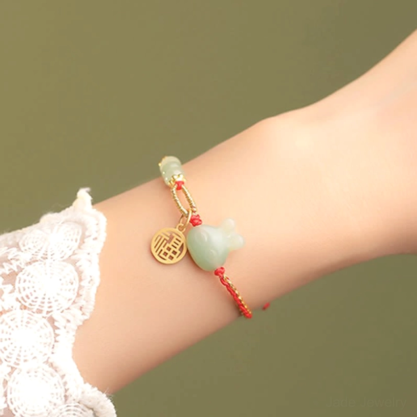 Red string jade rabbit fortune bracelet on model wrist, showing metal accents and jade beads