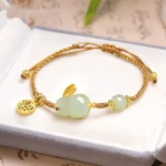 Year of the Rabbit Hetian jade bracelet with golden Fu charm in luxury jewelry box, top view