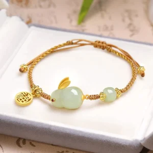 Year of the Rabbit Hetian jade bracelet with golden Fu charm in luxury jewelry box, top view