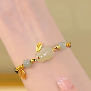 Adjustable rabbit zodiac string bracelet worn on wrist showing pale jade beads and gold-plated hardware