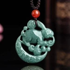 Reverse side of jade rabbit moon pendant showing intricate hollow carving details, red agate bead on black adjustable cord