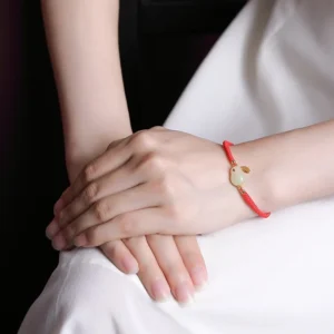 Hetian white jade rabbit zodiac bracelet worn on wrist, showing daily wear styling with minimalist aesthetic and red protective cord