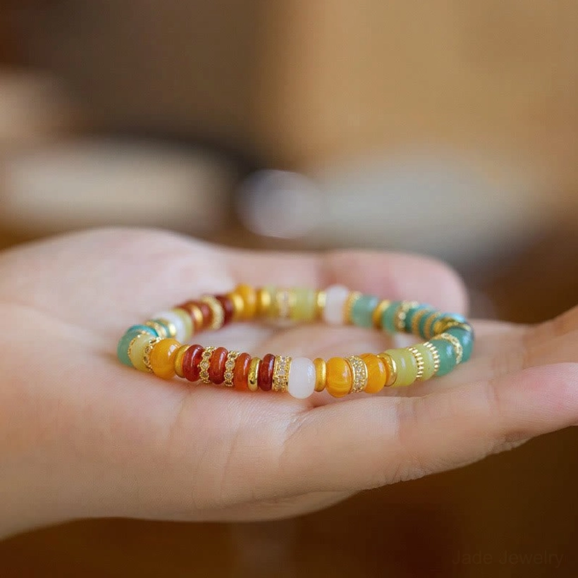 Rainbow jade agate bracelet on open palm showing bead detail and mixed warm cool stone tones