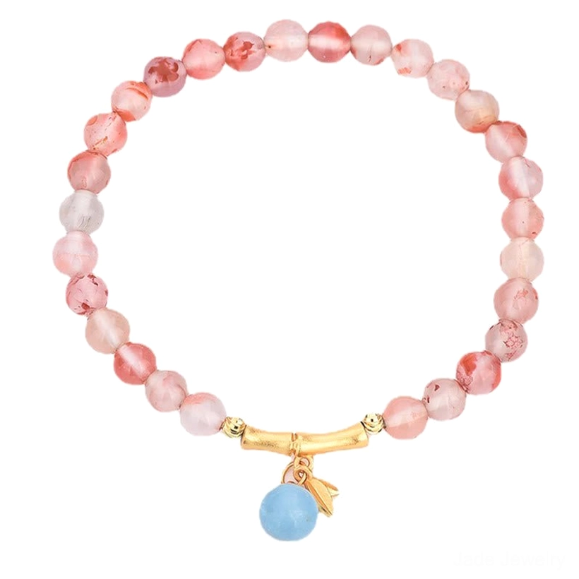 South Red Agate prosperity bracelet with gold bamboo joint charm and aquamarine drop pendant on light background