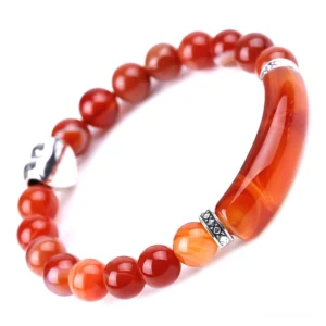 Red agate crystal beaded bracelet flat lay with silver heart charm and metal accessories