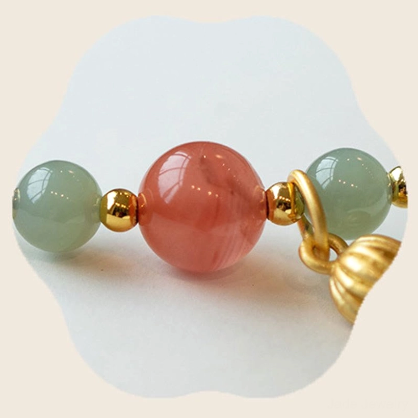 Macro view of red agate and jade beads in lotus prosperity bracelet with gold accents