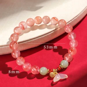 Red agate luck bracelet with white jade fishtail charm on wooden tray, displaying 8mm bead size and mixed agate-jade composition