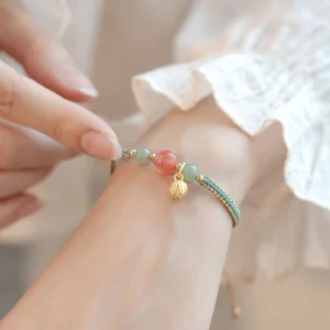Hand adjusting red agate jade lotus stone bracelet with adjustable closure detail