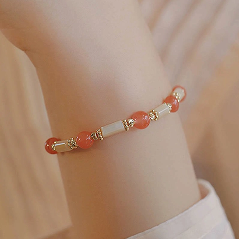 Red agate beaded bracelet with shell tube beads worn on wrist close-up, shirt sleeve styling detail