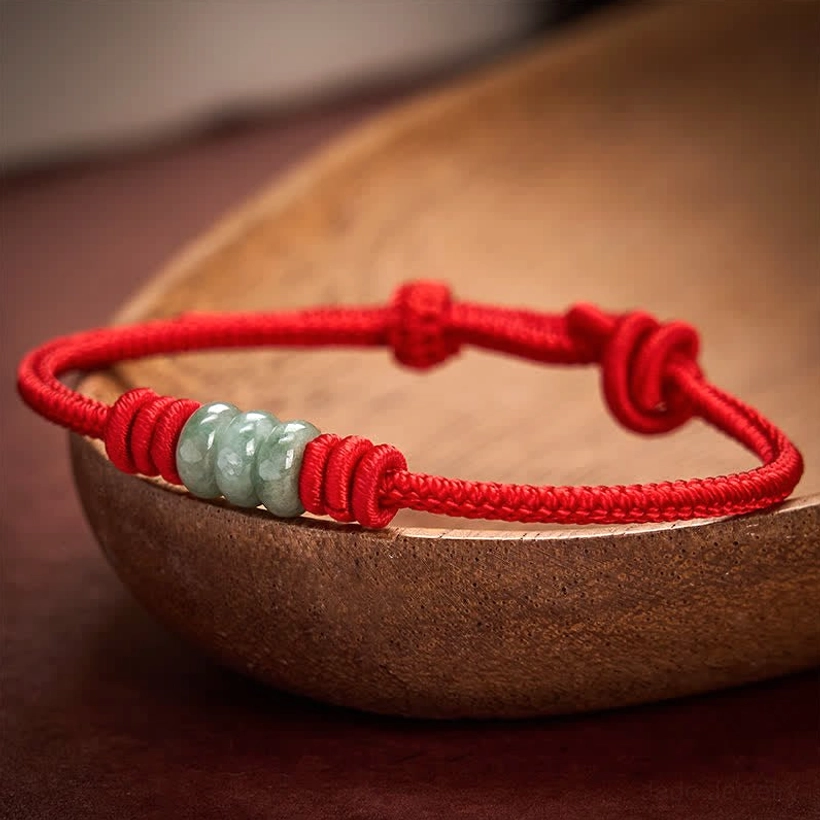 Pair of red string jade bracelets featuring adjustable sliding knots and jade bead clusters in tabletop styling