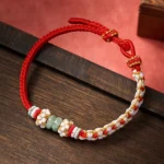 Red peach blossom jade bracelet handmade Chinese knot detail on wooden surface