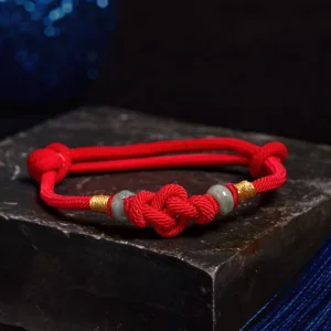 Handcrafted red string jade couple bracelet overhead view with knotted cord and adjustable jade beads