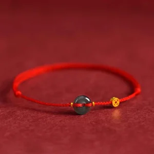 Red string jade peace buckle bracelet with copper coins on dark background, front flat view showing adjustable sizing