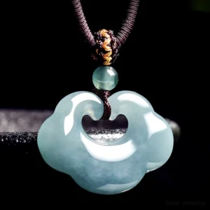 Three-quarter angled view of light cyan polished Ruyi jade lock pendant with small jade bead accent on adjustable brown braided cord with gold threading details