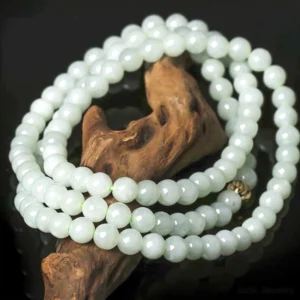 Natural jade 108 bead mala meditation necklace - hand-polished white beads with gold-toned metal clasp, overhead flat lay view showing smooth polished surface and bead uniformity